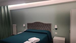 a bedroom with a green bed with two white towels at B&B La Dimora di Gioacchino in San Giovanni in Fiore