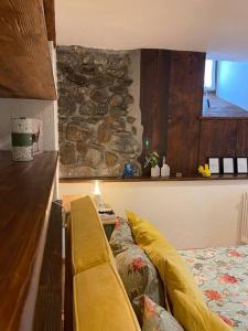 a yellow couch in a room with a stone wall at La Bombetta Gialla di Elisa e Marco in Morgex