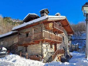 a log cabin in the snow with a balcony at La Bombetta Gialla di Elisa e Marco in Morgex