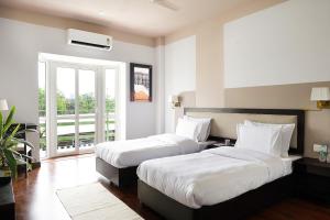 a hotel room with two beds and a balcony at Firebrick Boutique Residences - AMETHYST HOUSE in Gurgaon