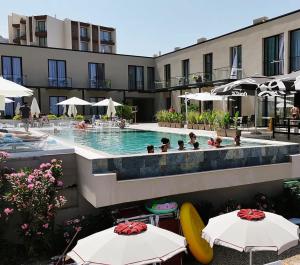 a swimming pool with tables and umbrellas in front of a building at Dukes Albania in Vlorë