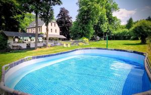 a large swimming pool with a house in the background at 3 Peaks Houses - Domki Całoroczne in Sokołowsko