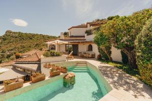 a villa with a swimming pool in front of a house at Aethos Hotel Sardinia in Cannigione