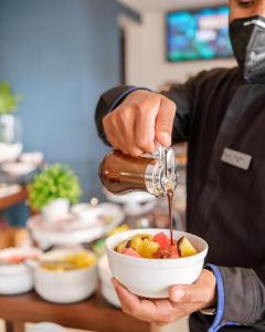 a person pouring syrup into a bowl of food at Hodelpa Caribe Colonial in Santo Domingo