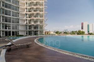 a swimming pool with a bench next to a building at RedLiving Apartemen Majestic Point Serpong by Lucia in Tangerang