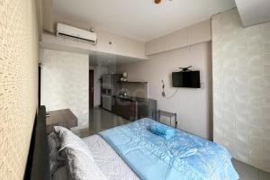 a bedroom with a blue bed and a kitchen at RedLiving Apartemen Majestic Point Serpong by Lucia in Tangerang