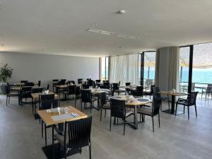 a dining room with tables and chairs and windows at Dukes Albania in Vlorë