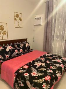 1 dormitorio con 1 cama con manta negra y rosa en spacious condo unit 1P olvera residences, en Bacolod