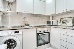 una cocina con gabinetes blancos y una lavadora y secadora en Sunflower Tailandia_Santa Pola, en Santa Pola 13 fotos más