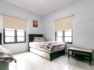 a white bedroom with a bed and two windows at Stylish Villa at Green Apple U 35A Cipanas Puncak in Sindanglaya