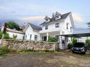 a white house with a car parked in front of it at Stylish Villa at Green Apple U 35A Cipanas Puncak in Sindanglaya