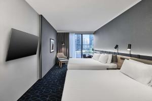 a hotel room with two beds and a chair at Vibe Hotel Melbourne Docklands in Melbourne
