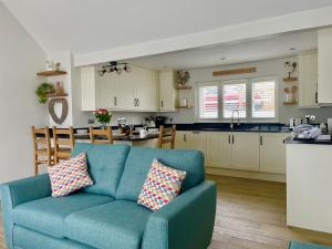 a living room with a blue couch and a kitchen at Sunny Bank in Holsworthy