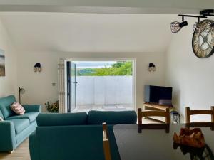 a living room with a blue couch and a clock at Sunny Bank in Holsworthy