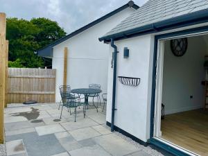 a white shed with a table and chairs on a patio at Sunny Bank in Holsworthy