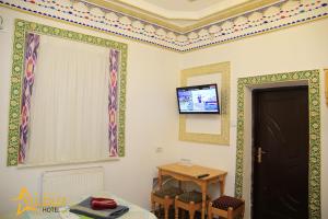 Cette chambre dispose d'une table et d'une télévision murale. dans l'établissement Ark & Yulduz, à Boukhara
