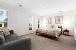 a white bedroom with a bed and a couch at Seachange Family Escape with Pool and Spa Bath in Saint Leonards