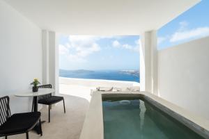 a bathroom with a swimming pool and a table and chairs at Rocabella Santorini Hotel & Spa in Imerovigli