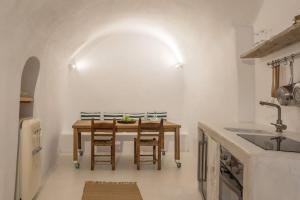イアにあるWhite Cellar cave houses by Cycladicaの木製のテーブルと椅子のあるキッチン +39枚の写真