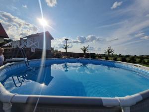a large swimming pool with the sun in the sky at Agroturystyka Bocian Biały in Kiwity