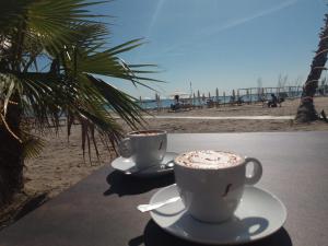 two cups of coffee sitting on a table near the beach at Studio Lido 10 in Lido delle Nazioni