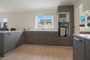 a kitchen with brown cabinets and a sink and a microwave at Deeside Brae Villa Grampian Lettings Ltd in Aberdeen