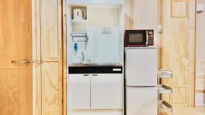 a small kitchen with a microwave on top of a refrigerator at ATTA Toya - Dome Gramp in Date