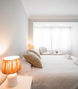 a white bedroom with a large bed with a lamp at EnjoyGranada RECOGIDAS HOMES in Granada