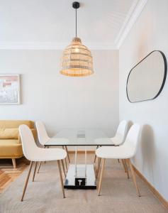 a dining room with a glass table and white chairs at EnjoyGranada RECOGIDAS HOMES in Granada