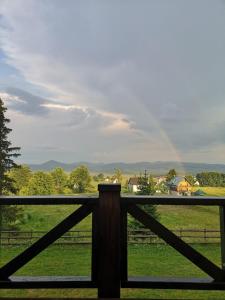 a rainbow in the sky over a field with a fence at Razvršje Co in Žabljak