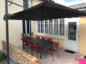 un tavolo nero e sedie sotto un ombrellone su un patio di La Grande Carelle a Fagnières