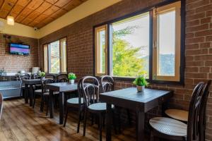 un restaurant avec des tables, des chaises et des fenêtres dans l'établissement Pet-Friendly mountain view 2 bedroom cottage C1, à Mukteswar