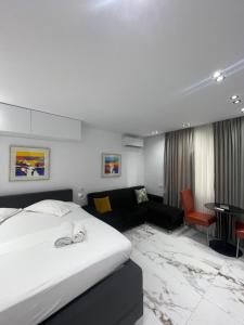 ティラナにあるMidnight Apartmentsのベッドとソファのあるホテルの部屋