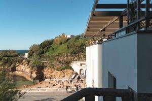a building with a view of a hill with people at Hôtel de La Plage in Biarritz