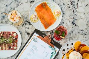 a table topped with plates of food and a menu at Hôtel de La Plage in Biarritz +37 photos