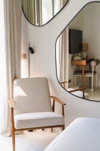 a bedroom with a chair and a mirror at Hôtel de La Plage in Biarritz