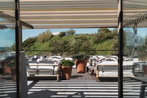 a patio with white chairs and a hill in the background at Hôtel de La Plage in Biarritz