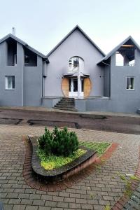 una casa blanca con un árbol delante en Cozy Family Apartments, en Druskininkai