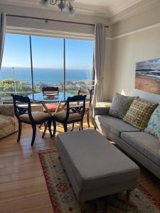 a living room with a couch and a table with a view at Little Penguin in Simonʼs Town