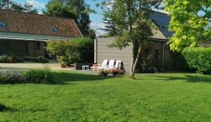 a yard with two white chairs and a table at De Groene Hoeve in Brakel