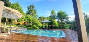 einen Pool auf einer Holzterrasse mit einem Sonnenschirm in der Unterkunft Kilar Mountain Villa in Zeren