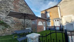 a picnic table with an umbrella in a yard at Le Scailleteux, petite maison de mineur, climatisée non accessible PMR in Fumay