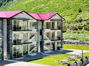 纳兰恩Kunhar Hotel RiverSide Block的一座带有粉色屋顶和草坪的大型建筑