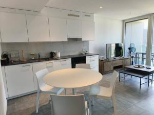 a kitchen with a table and white cabinets and a table and chairs at LabPark enjoy Melano in Melano