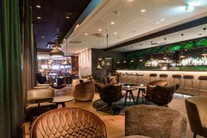 ein Restaurant mit einer Bar mit Stühlen und Tischen in der Unterkunft Motel One Freiburg in Freiburg im Breisgau