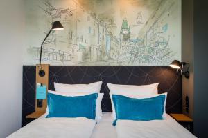 ein Schlafzimmer mit einem Bett mit zwei blauen Kissen in der Unterkunft Motel One Freiburg in Freiburg im Breisgau