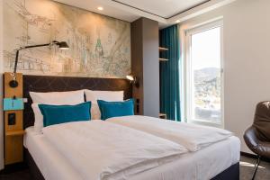 ein Hotelzimmer mit einem großen Bett mit blauen Kissen in der Unterkunft Motel One Freiburg in Freiburg im Breisgau