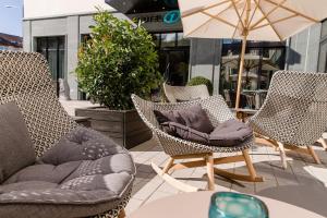 eine Terrasse mit 3 Stühlen und einem Tisch mit einem Sonnenschirm in der Unterkunft Motel One Freiburg in Freiburg im Breisgau