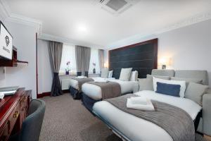 a hotel room with three beds and a television at Gem Fitzrovia Hotel in London