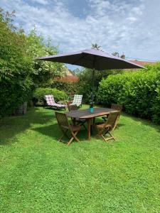 a wooden table and chairs under an umbrella at Studio à 15mn de Beaune in Saint-Loup-Géanges